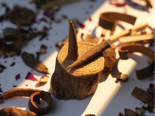 Handcrafted Sera Serene Tibetan incense cones on a rustic holder, surrounded by herbal ingredients in warm afternoon light.