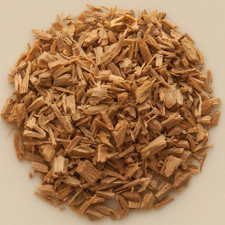 A pile of white sandalwood chips (a key ingredient of Tibetan incense) arranged neatly on a clean white surface, showcasing the smoothness and light color of the wood.