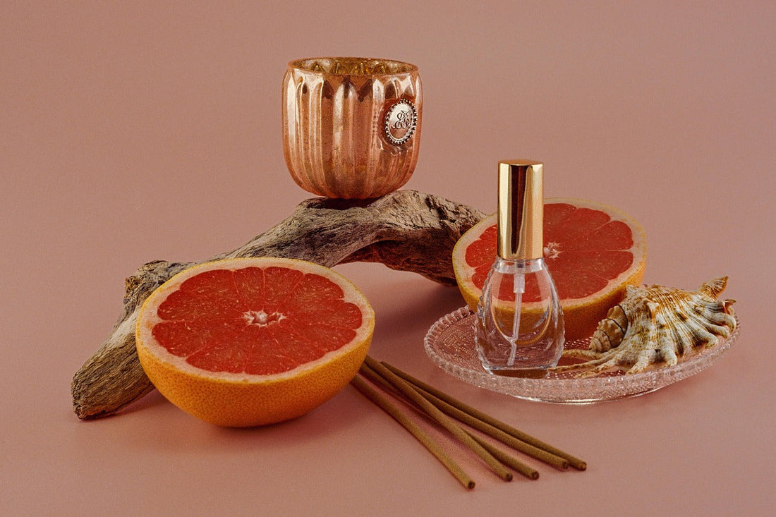 A calming aromatherapy scene with incense sticks, grapefruit, candle, and perfume bottle, illustrating how scent rituals like incense burning can ease anxiety, lower stress hormones, and ground the mind.