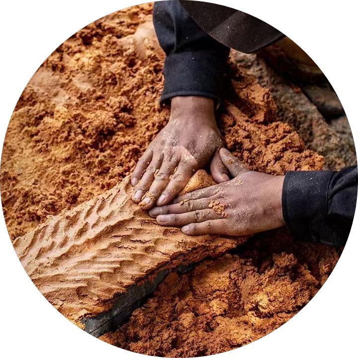 A craftsman processes cypress pulp into blocks with two hands, diligently working on a wooden piece, leaving  traces of fingers.