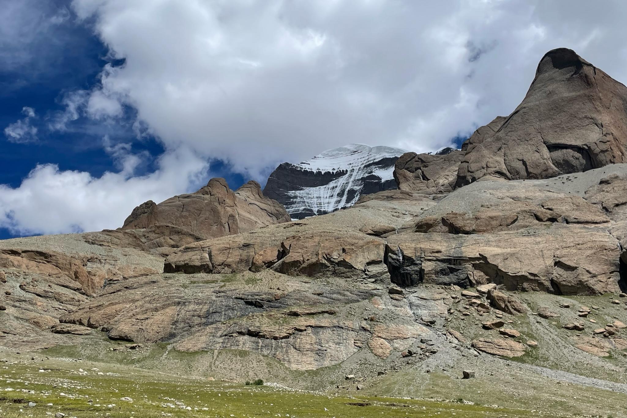  A towering, rocky mountain rises majestically against the clear sky in Tibet.