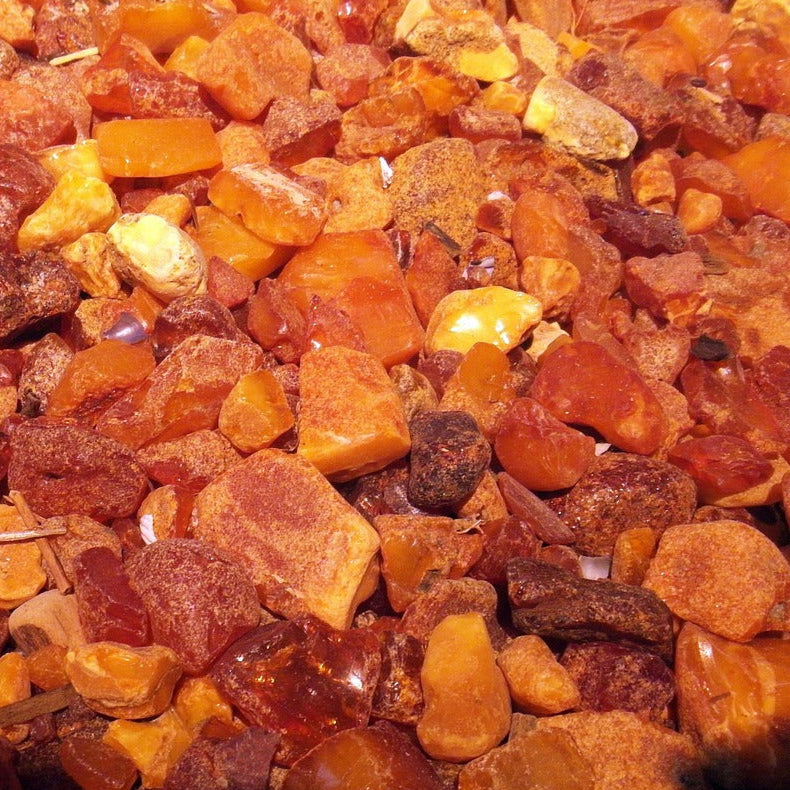 A circular formation of amber stones, a key ingredient of Tibetan incense,  featuring warm orange and yellow tones that emphasize their organic elegance.
