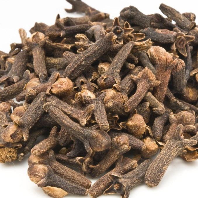 A close-up view of multiple cloves (a key ingredient of Tibetan incense) arranged closely together, showcasing their rich brown color and unique texture.