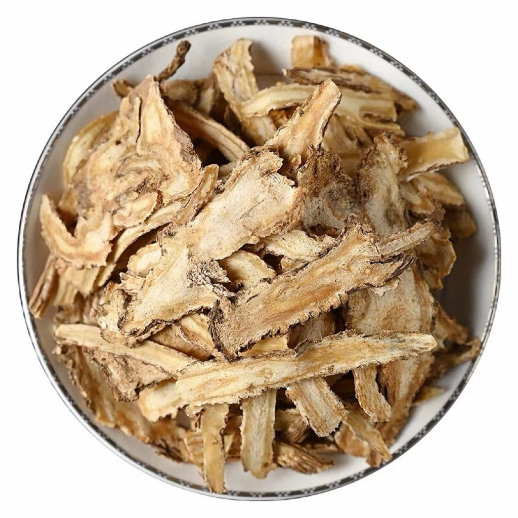 Dried dong quai (Angelica sinensis), a key ingredient of Tibetan incense, in a white bowl on a white background.