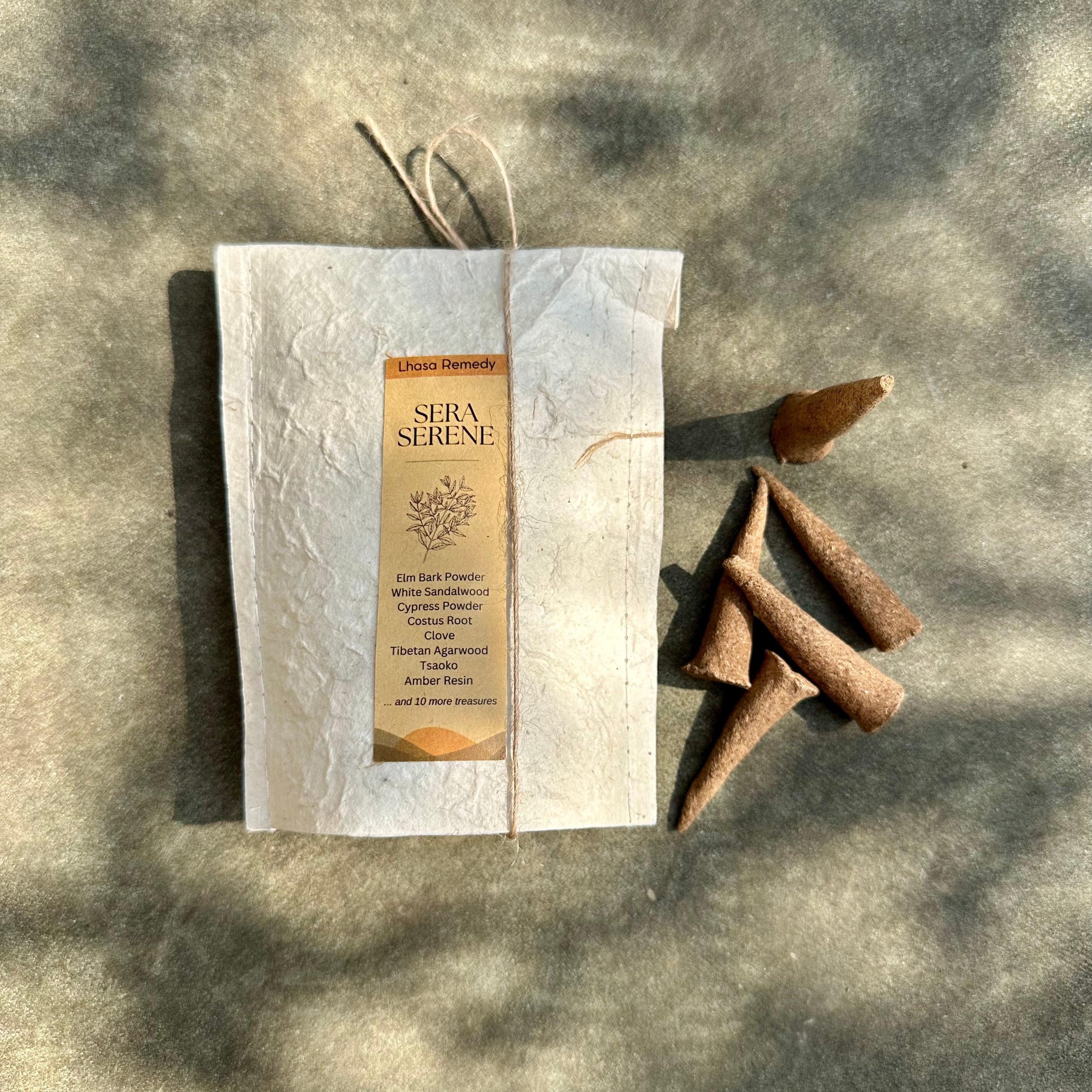 A collection of incense cones in a bag with a rope and product label of "Sera Serene" next to a small pouch of incense cones, resting on the ground.
