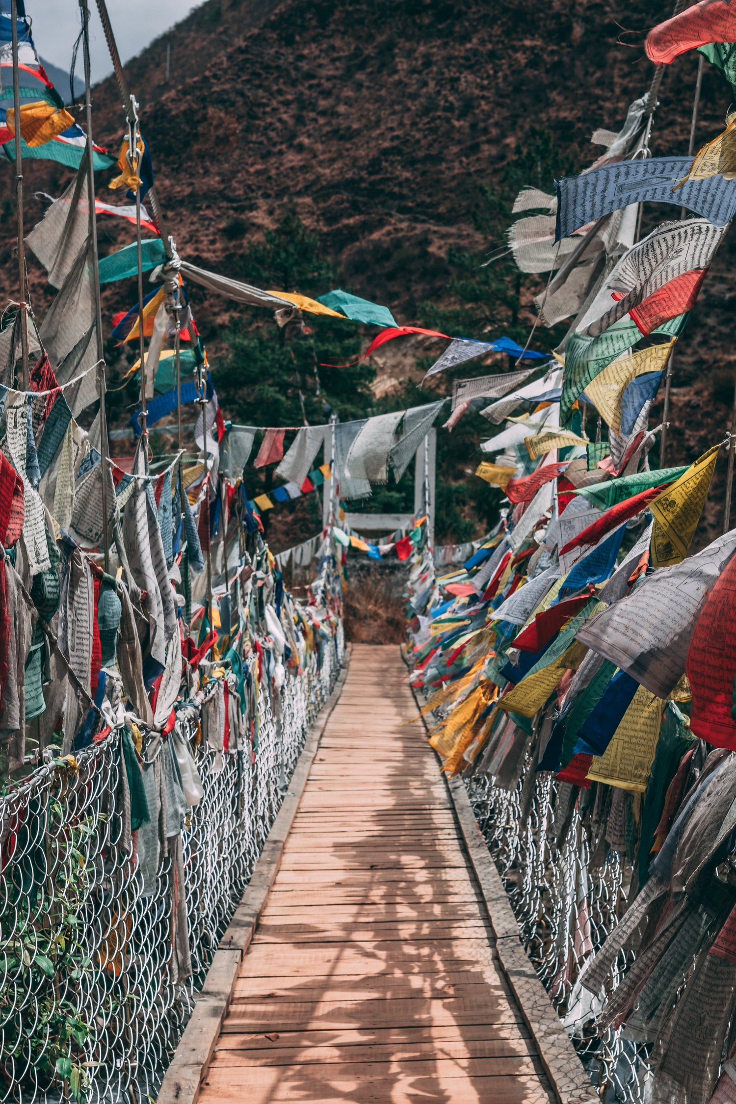 A bridge decorated with vibrant prayer flags, representing Tibetan culture and spiritual beliefs.