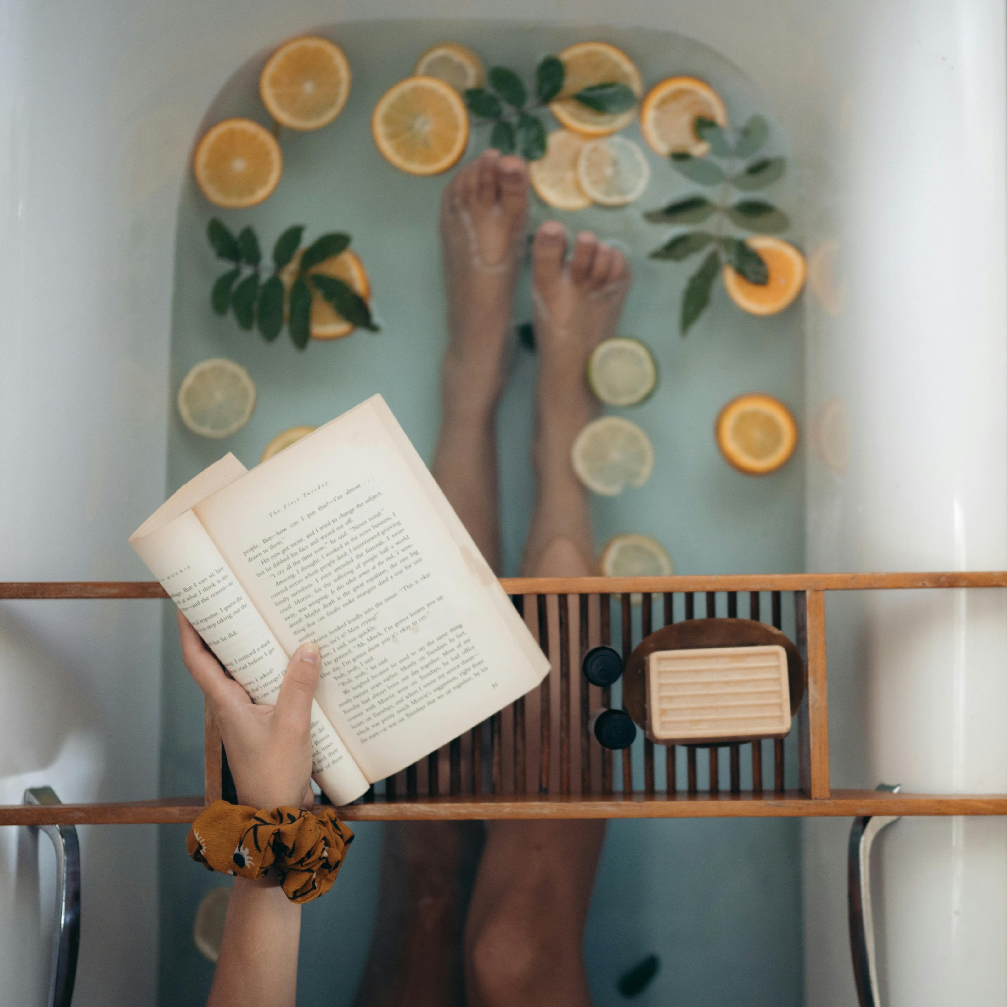 A serene scene of a person enjoying a book in a bathtub, with vibrant lemons adding a touch of freshness.