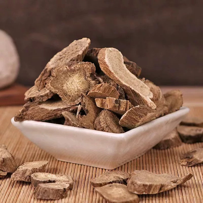 Dried  Inula Racemosa wood (a key ingredient of Tibetan incense) from Tibet in a white bowl on a wooden surface, emphasizing the wood's intricate details and textures.