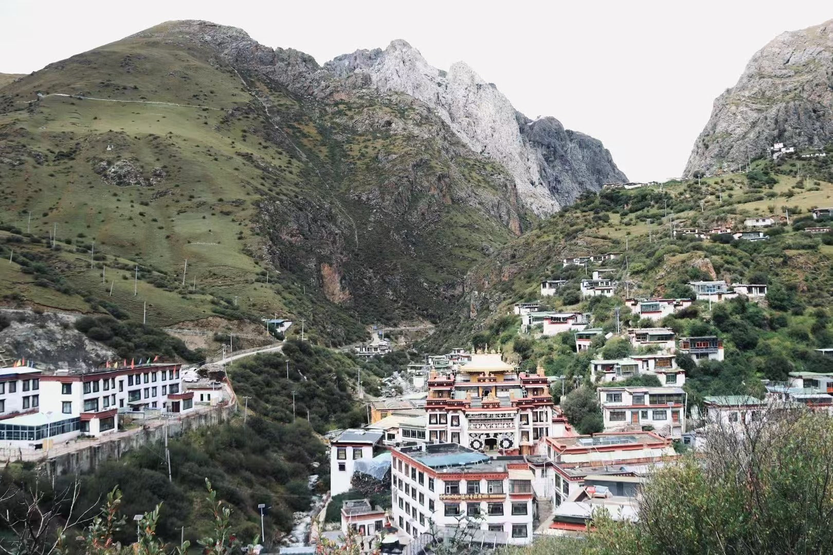 Scenic view of a Tibetan mountain village, showcasing traditional architecture against a dramatic mountainous landscape.