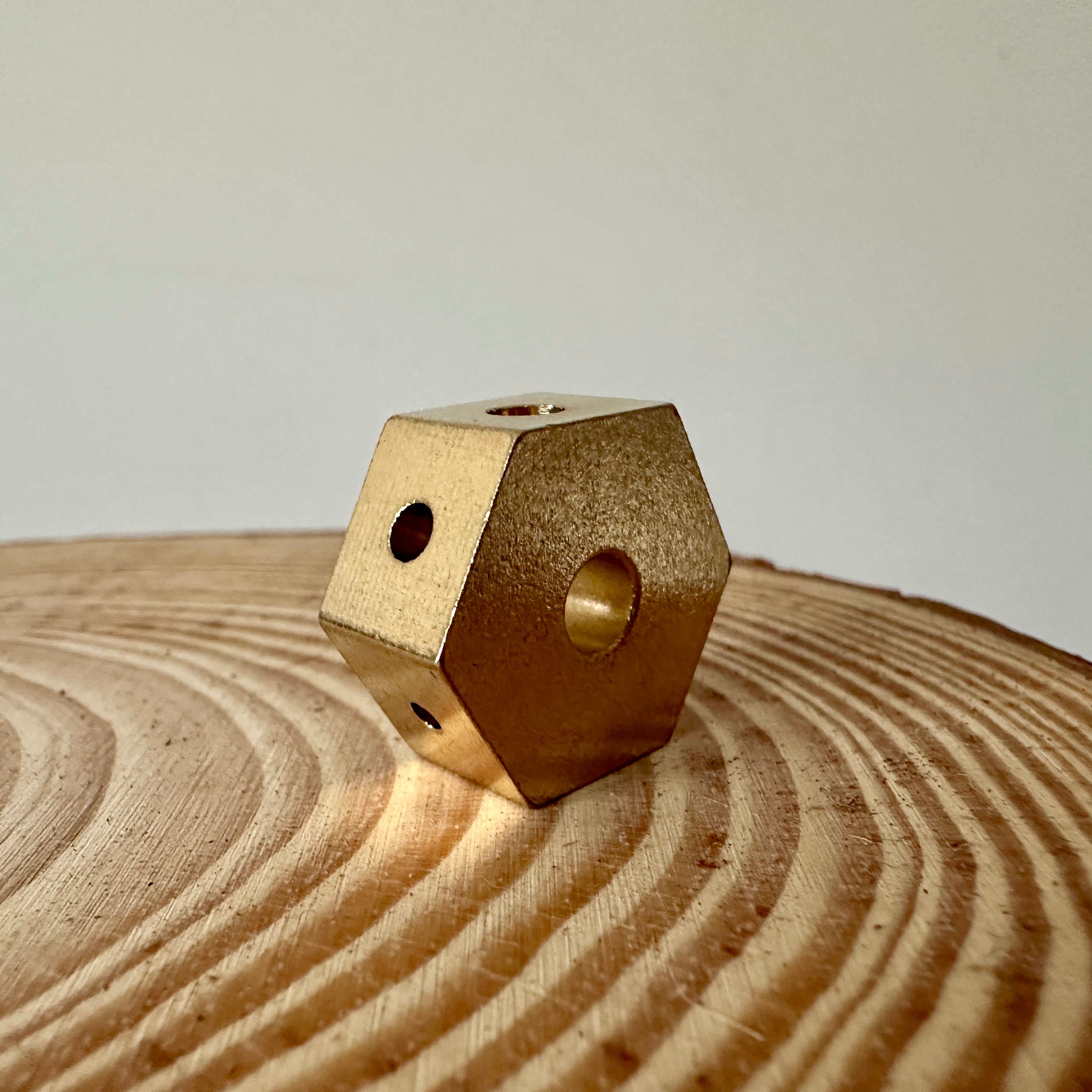 A small brass four-hole incense holder placed on a circular wooden surface with a plain white background.