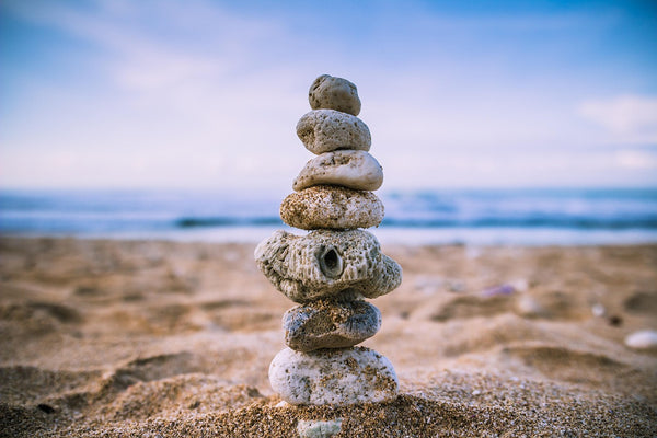 A tower of stacked stones on the sandy beach, symbolizing mindfulness, balance, and calm.